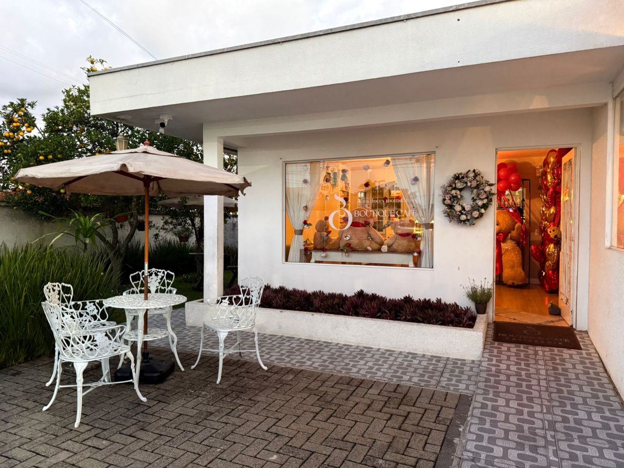 Fachada da Boutique Café em Araucária com mesa externa e vitrine iluminada